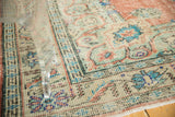 Distressed Oushak rug with visible worn texture in mint green, blue, and terracotta floral motifs.