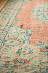 Distressed Oushak pile with Rococo motifs in dusty rose terracotta and mint green.