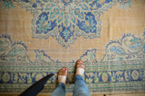 Decorative distressed Oushak carpet, showing worn apricot field and navy blue palmettes.