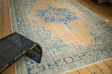 Distressed vintage Oushak rug corner, featuring Rococo stylized European motifs in apricot, navy, and mint.