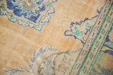 Textural detail of distressed Oushak rug, apricot field, navy blue motifs, and visible foundation.