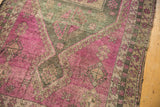 Geometric purple and charcoal motifs on a distressed vintage Oushak runner showing foundation.