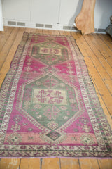 Distressed vintage Oushak runner with central pinwheel and abrashed magenta, sage green field.