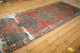 Worn geometric border detail of distressed Oushak runner in brick red and oxidized silver.