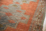 Distressed texture of an Oushak runner, highlighting geometric vine lattice in oxidized silver and madder red.