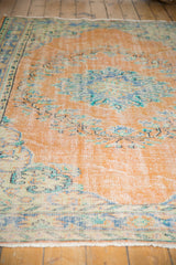 Distressed Oushak pile in apricot, mint, and blue with even wear, faded floral motifs.