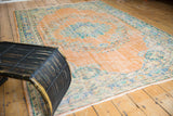 Distressed Oushak rug corner, apricot peach field, worn floral motifs, and fringe.