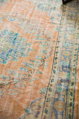 Apricot peach distressed Oushak rug pile with faded mint green and blue floral motifs.