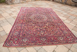 Angled view of vintage Isfahan rug, intricate medallion and covered field, deep purple and red.