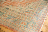 Distressed Oushak rug corner; even wear highlights terracotta, ivory, and ocean blue floral motifs.