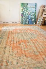 Distressed texture of a vintage Oushak rug with faded terracotta and ocean blue-green.