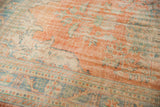Even wear across a distressed Oushak rug, revealing pale terracotta and blue-green floral motifs.