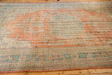 Distressed vintage Oushak carpet, faded terracotta, ocean blue-green, and antique ivory tones.