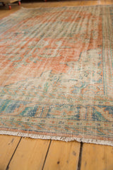 Distressed Oushak rug pile shows even wear, pale terracotta, ocean blue, and ivory fringe.