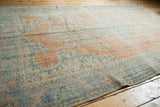 Distressed vintage Oushak rug showing worn knot heads, pale tangerine, and faded blue motifs.