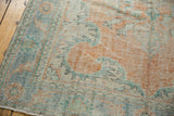 Distressed Oushak rug corner, European scrolling motifs, faded ivory, orange, mint, blue hues.