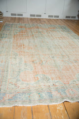 Faded tangerine, mint, and blue palette on a distressed Oushak rug's low pile.