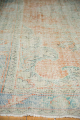 Vintage distressed Oushak rug pile with faded tangerine, mint, and blue.