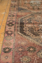 Decorative distressed pile on vintage Oushak runner, showing blush, charcoal, and rose border motifs.