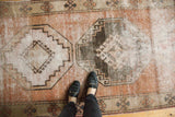 Distressed Oushak runner with worn geometric medallions, foundation showing, in brick, ivory, brown.