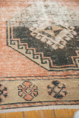 Distressed Oushak runner's textured pile, showing hooked medallion and geometric border.