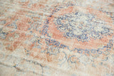 Distressed Oushak rug with faded rose blush and denim blue vinery, revealing knot heads.