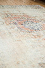 Distressed Oushak carpet texture showing faded rose blush, ivory, denim blue with exposed knot heads.