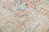 Even wear across the distressed rose blush Oushak rug, revealing royal blue motifs.