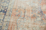 Distressed Oushak carpet texture: rose blush, ivory, denim blue motifs, exposed knot heads.