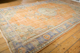Distressed Oushak rug, textured pale tangerine field with faded royal blue and ivory border.