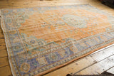 Distressed vintage Oushak carpet showing worn tangerine orange field and faded blue border.