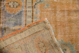 Vintage distressed Oushak rug's worn pile, visible foundation, and secured orange side binding.