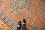 Worn texture of a distressed Oushak carpet, showing faded patterns in pale red, blue, and ivory.
