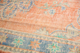 Distressed Oushak carpet with worn pale red pile, sky blue border, Rococo style patterns.