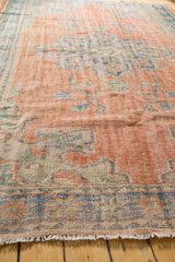 Distressed Oushak rug edge with worn pile texture and short ivory fringe.
