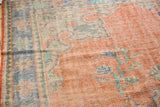 Distressed vintage Oushak detail: worn pale red field with scrolling sky blue vinery.