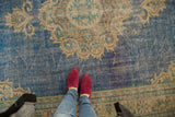 Distressed texture of vintage Oushak rug, blue field with antique ivory scalloped medallion.