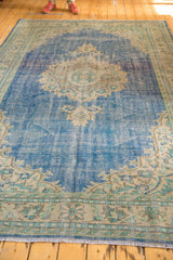 Decorative vintage distressed Oushak rug featuring blue field, light roundel medallion, and soft texture.