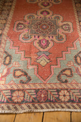 Detail of the distressed Oushak rug runner's blush, sea foam, and charcoal stepped geometric pattern.