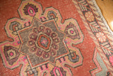 Worn blush pink, rose, and charcoal scalloped medallion detail on a distressed Oushak runner.