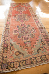 Distressed Oushak runner end, stepped sea foam spandrel, blush paisley motifs, and fringe.