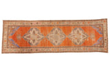 Vintage distressed Oushak runner with bold medallions on an abrashed tangerine orange field with blue corners.