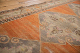 Worn texture revealing knot heads on the abrashed tangerine field and scrolling medallion outline.
