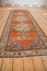 Long perspective of a distressed Oushak runner highlighting its tangerine orange field and repeating medallions.