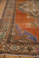 Close-up of the distressed Oushak runner's border and abrashed tangerine field with a royal blue corner.
