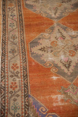 Scrolling medallion outlines and a floral border on a distressed tangerine orange Oushak rug.