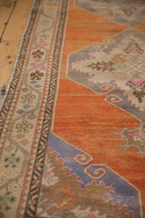 Scrolling blue outlines on an abrashed tangerine field next to a detailed floral border.