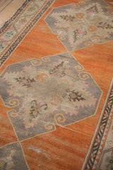 Decorative detail of a vintage Oushak medallion showing worn texture and scrolling floral motifs.