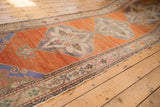 Angled view of a vintage Oushak runner's vibrant, abrashed orange field and repeating medallions.