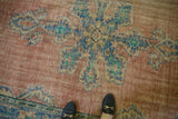 Distressed Oushak rug detail with worn pile, exposed foundation, faded blue and blush tones.
